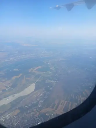 Still climbing, the wing over the water and the flat land beyond