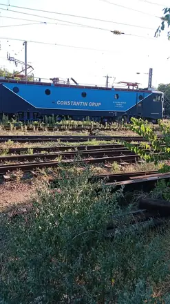 A Constantin Grup electric standing on a siding — 91 53 040 0725-4, RO-BEU, 120 km/h, one of the Class 40 machines that do the freight here. Grass through the ballast and spare rail in the four-foot beside it