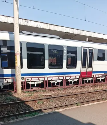 A second-class railcar at the platform with Sibiu in the window board, CFR winged wheels along the platform railing