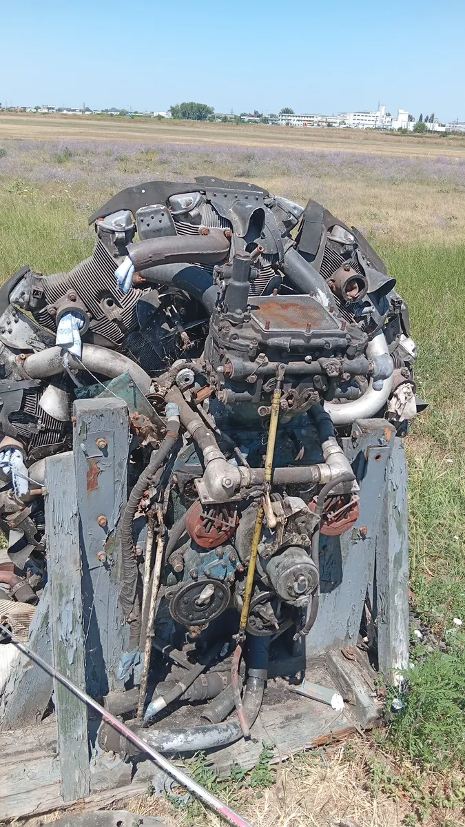 A stripped radial engine and airframe parts at the field edge