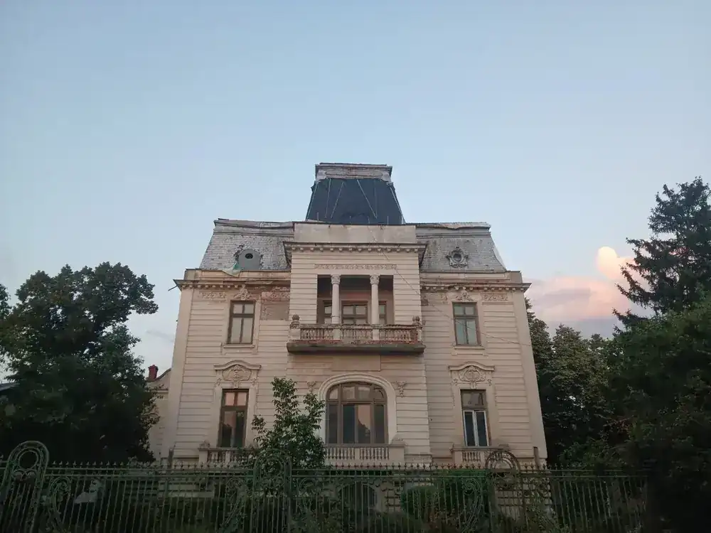 The street front at dusk — mansard, loggia and the original railings