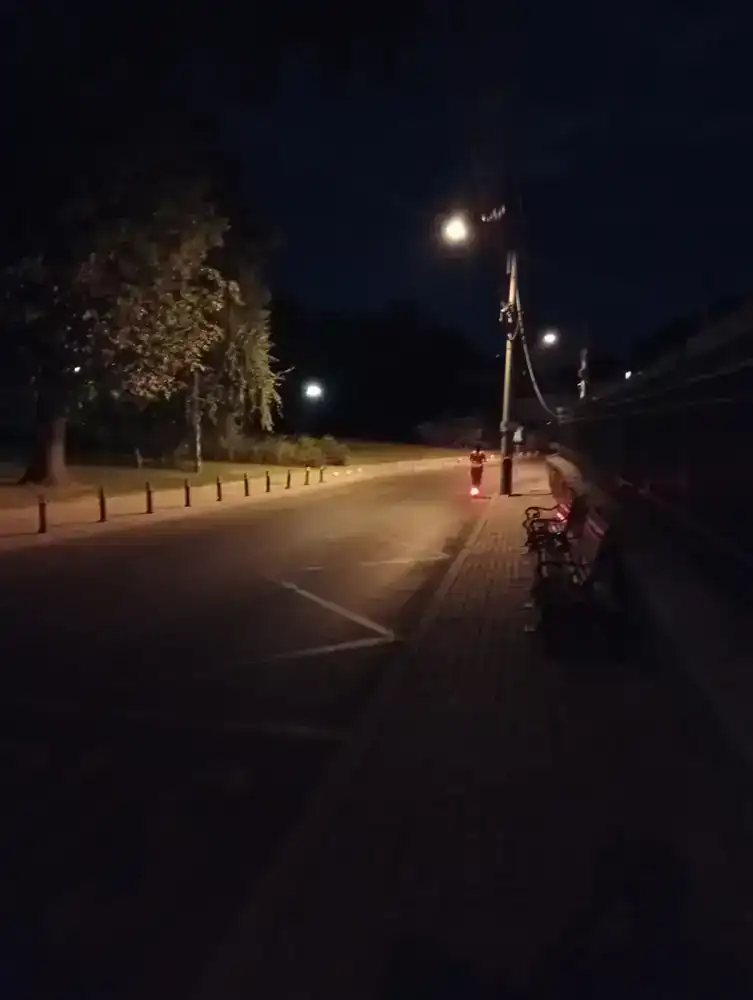 The same street a few steps on — a scooter's tail light the only traffic