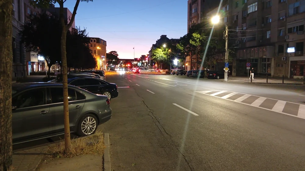 Blue hour on one of the boulevards — the last of the sunset at the far end, lamps already on, the cars parked up for the night. Street not yet named