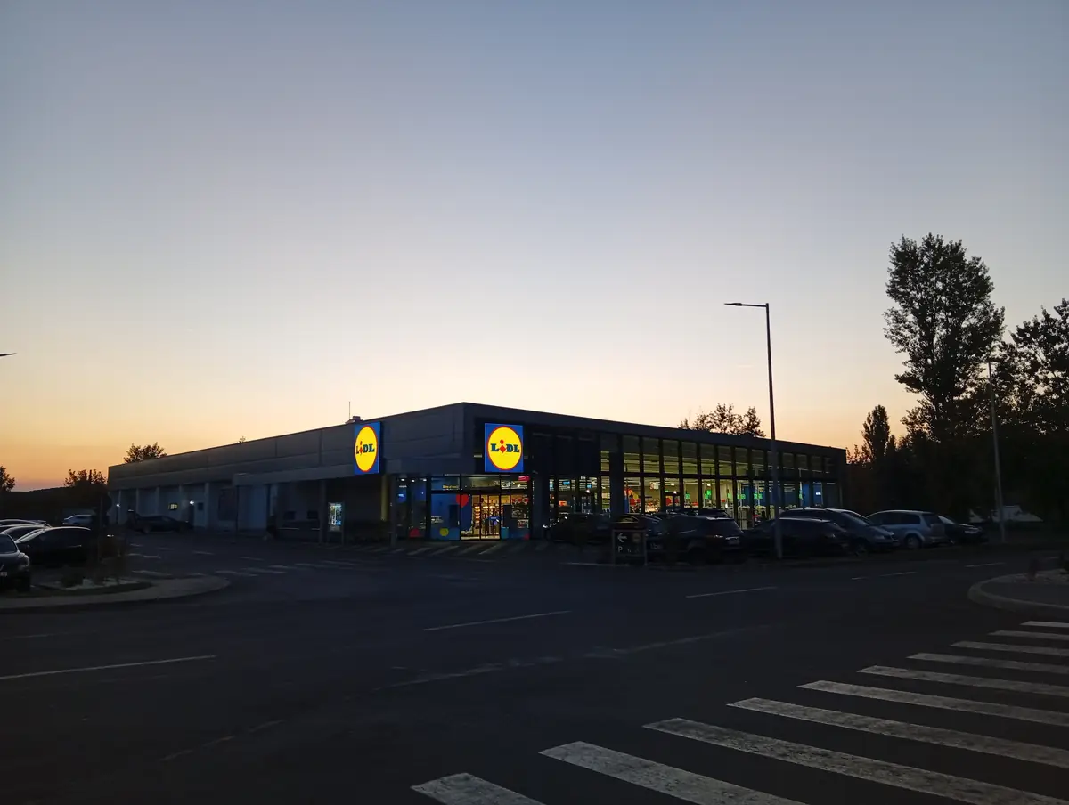 Lidl supermarket in Craiova at dusk, lit shopfront against an orange sunset sky, 20 September 2026
