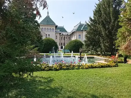 The fountain in English Park, Craiova, with the green roofs of the Palatul Administrativ behind it