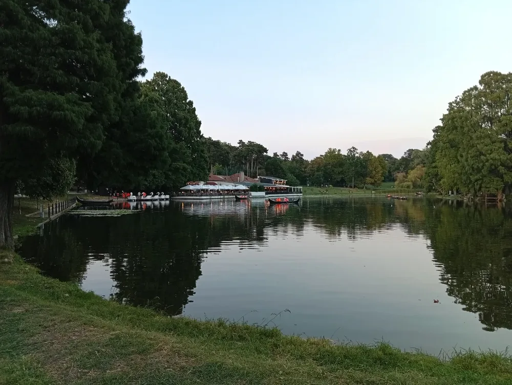 The lake at dusk — the terrace lit up on the far shore, gondolas and swan pedalos at the jetty