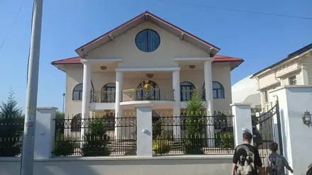 A large detached villa on a residential street in Craiova — columned porch, round gable window and gilded balcony ironwork