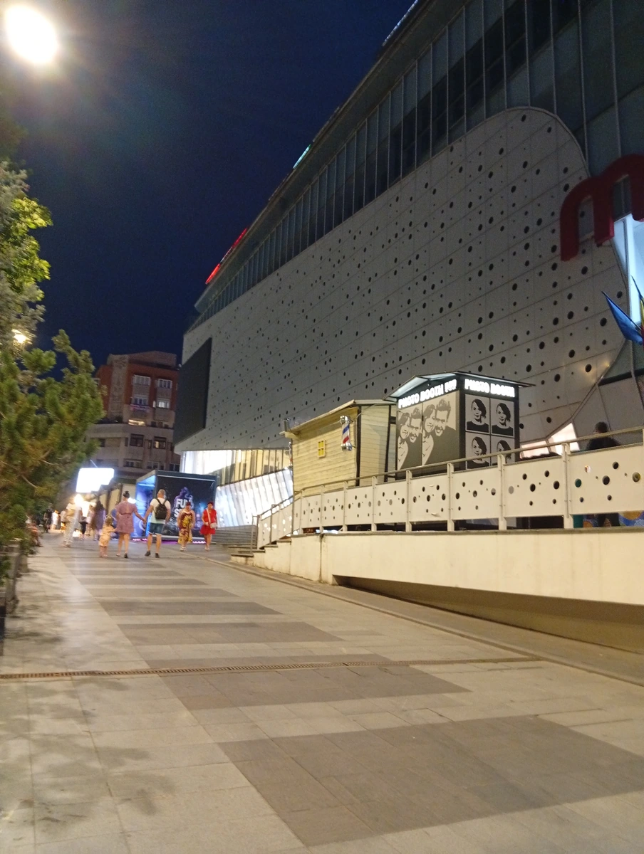 The pedestrian walkway along the building at night, photo booth by the entrance