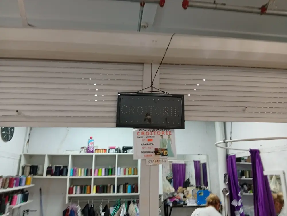 The thread wall behind another croitorie, opening hours pinned to the post