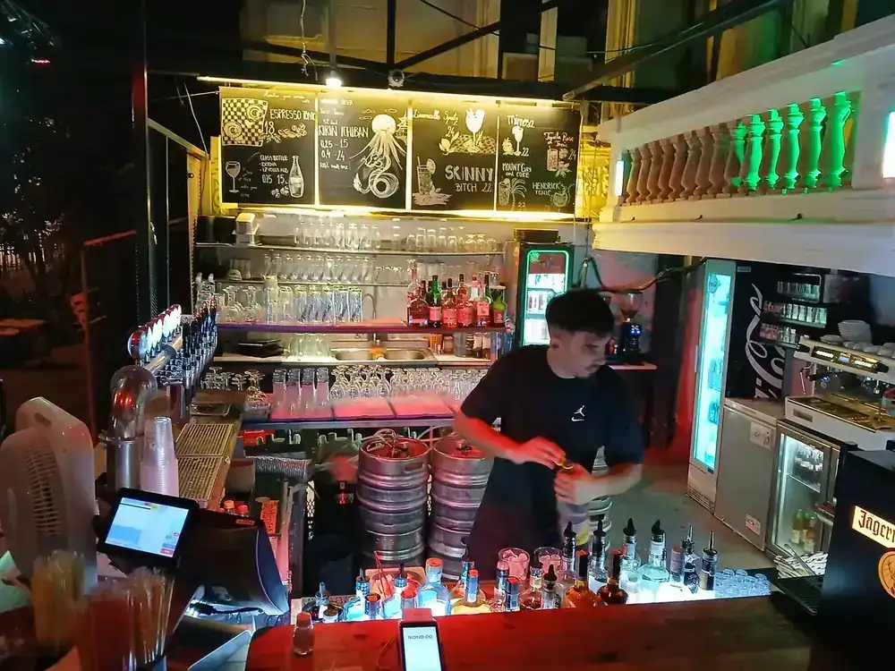 The main bar after dark — taps, kegs, and the lit chalkboards where the specials go up