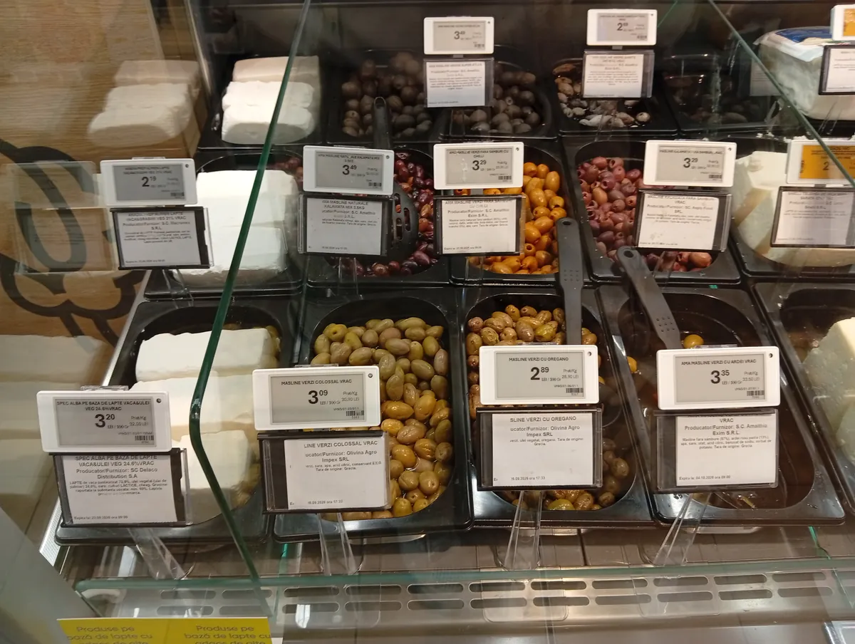 Loose olives at the Profi Super deli counter, Strada Henry Ford, Craiova area: green, Kalamata and black olives in trays with price labels per 100 g, 22 September 2026