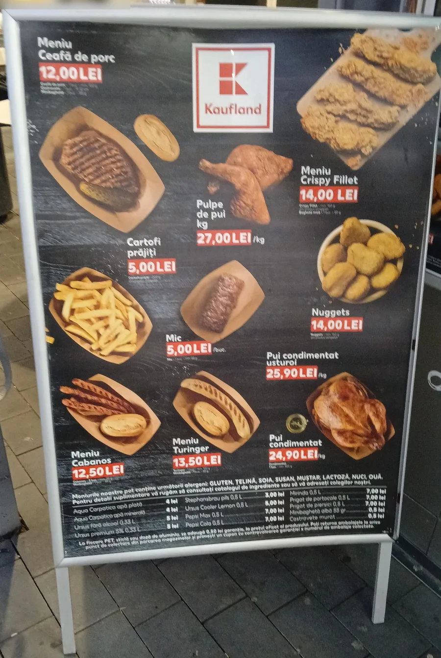 Menu board of a Kaufland grill counter in Craiova: pork neck, crispy fillet, cabanos and Thuringer menus, nuggets, fries, mici and rotisserie chicken by the kilo, prices in lei, 23 October 2026