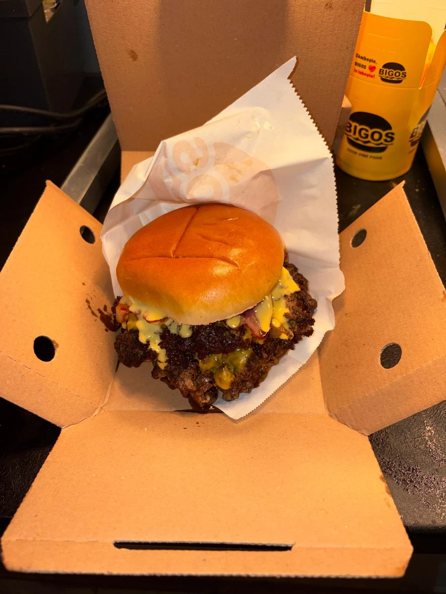 A double smash burger in its box, the BIGOS cup behind