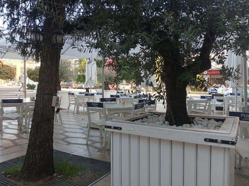 Tables under the olive trees, facing the square