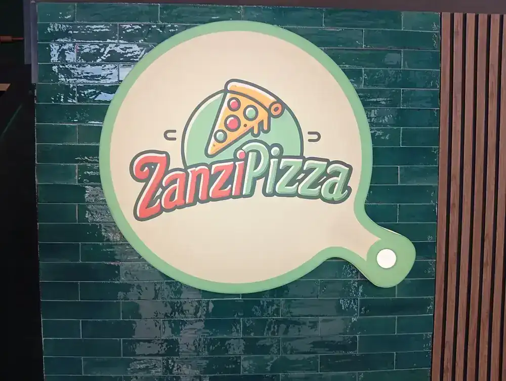 The ZanziPizza sign inside, on the green tile