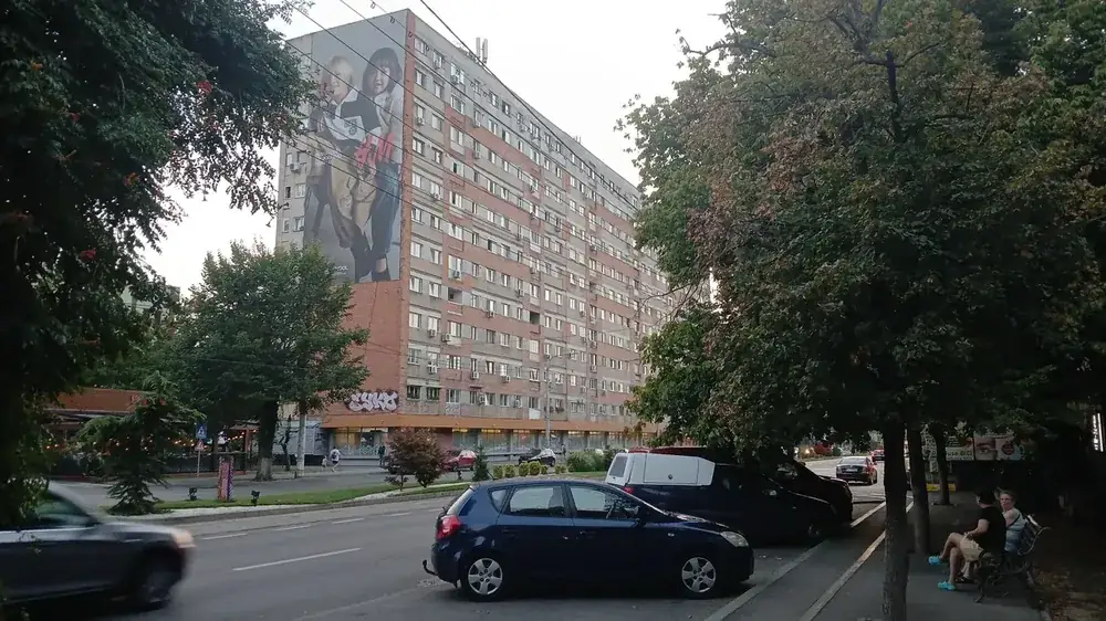 A long bloc on a main boulevard — shops along the ground floor, trees and a bus line at the door
